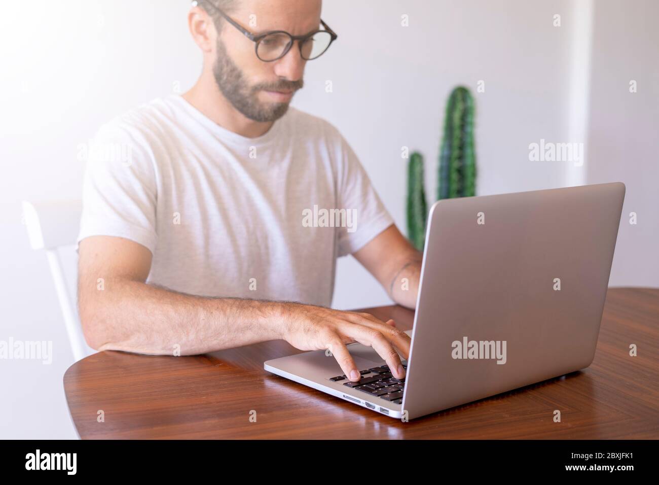 Giovane uomo con gli occhiali da schermo che scrivono sul computer che lavora da casa. Foto Stock