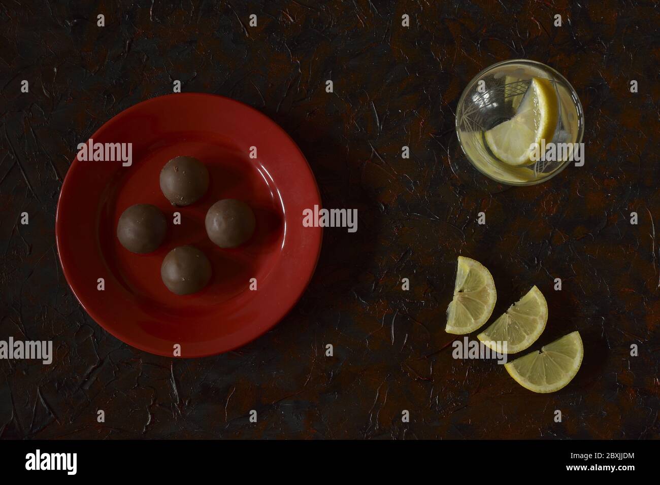 cioccolatini sul piatto e bevande con fette di limone servite sul tavolo Foto Stock