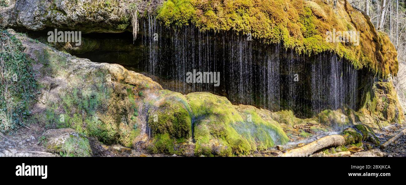 La cortina d'acqua nel Canyon di Wutach scintillante nella luce scintillante del sole di fronte al verde lussureggiante del muschio. Foto Stock