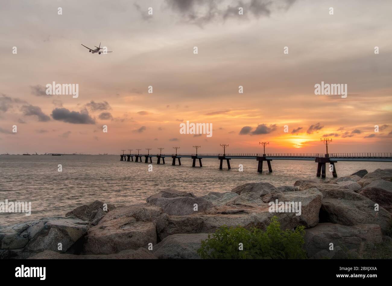 Vista costiera dell'aereo commerciale volare sul mare sotto il vibrante Sunset Sky, Hong Kong Foto Stock