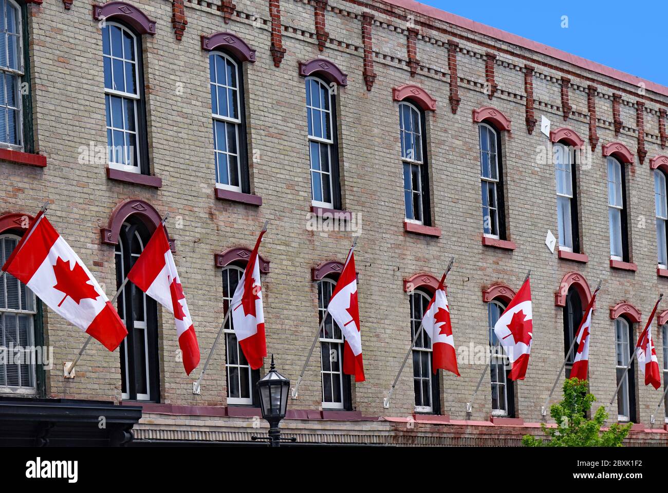 Vecchio edificio con fila di bandiere canadesi rosse e bianche di acero Foto Stock