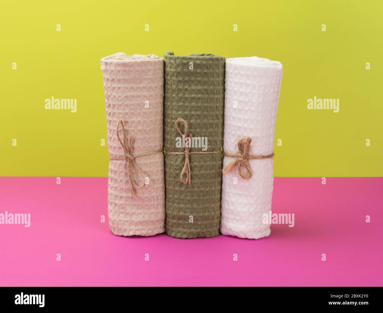 Tre asciugamani in stile ecologico su sfondo rosa e verde. Foto Stock