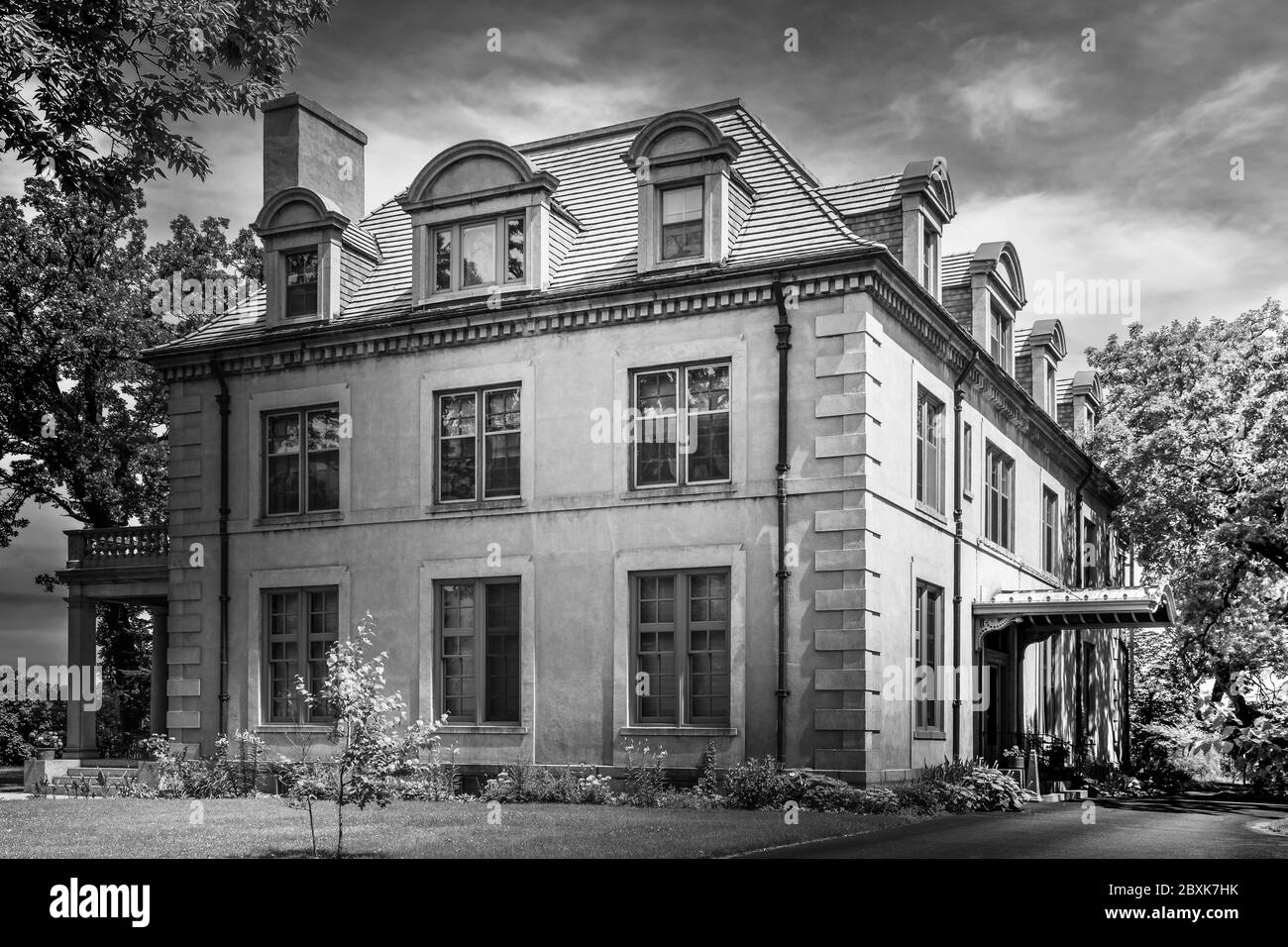 Una suggestiva villa francese in stile Beaux Arts, con un tetto mansarda con finestre ad arco in piccolo paese America, St. Cloud, MN, USA, in B&W. Foto Stock