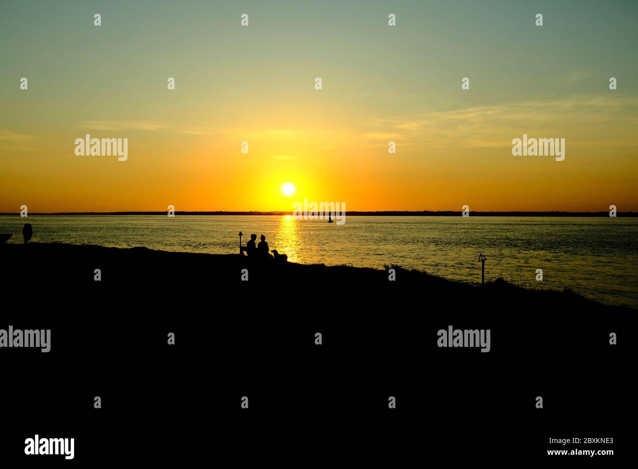 Una coppia siede su una panchina vista tramonto sul Solent a Sconce Point Fort Victoria Isola di Wight Foto Stock