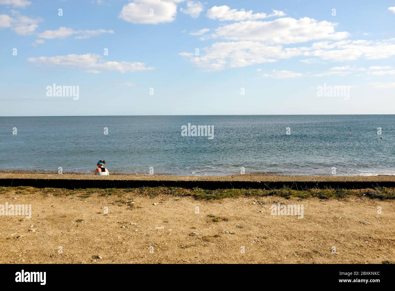 Si affaccia sul muro di mare della donna sulla spiaggia Foto Stock