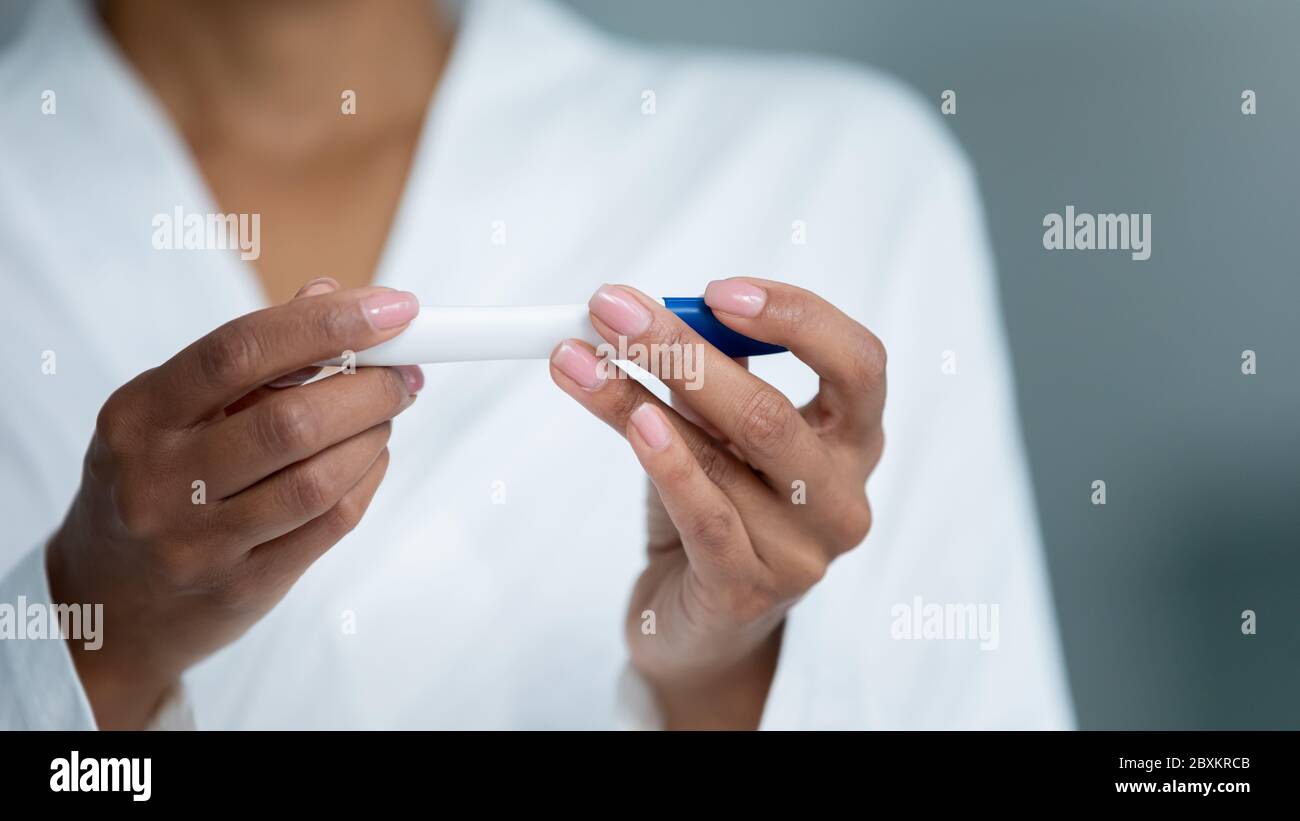 Primo piano donna afroamericana che tiene plastica tubo di prova di gravidanza Foto Stock