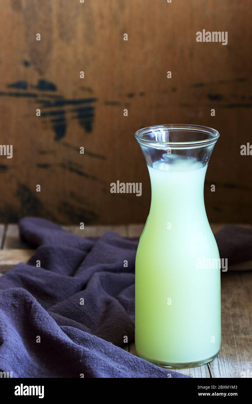 Siero di latte freddo in una bottiglia di vetro su uno sfondo di legno. Foto Stock