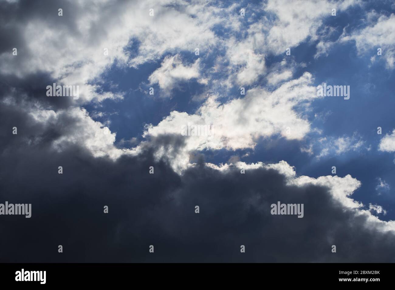 Sfondo del tempo con cielo sovrastato e nubi di cumulo scuro sotto durante una giornata di sole Foto Stock