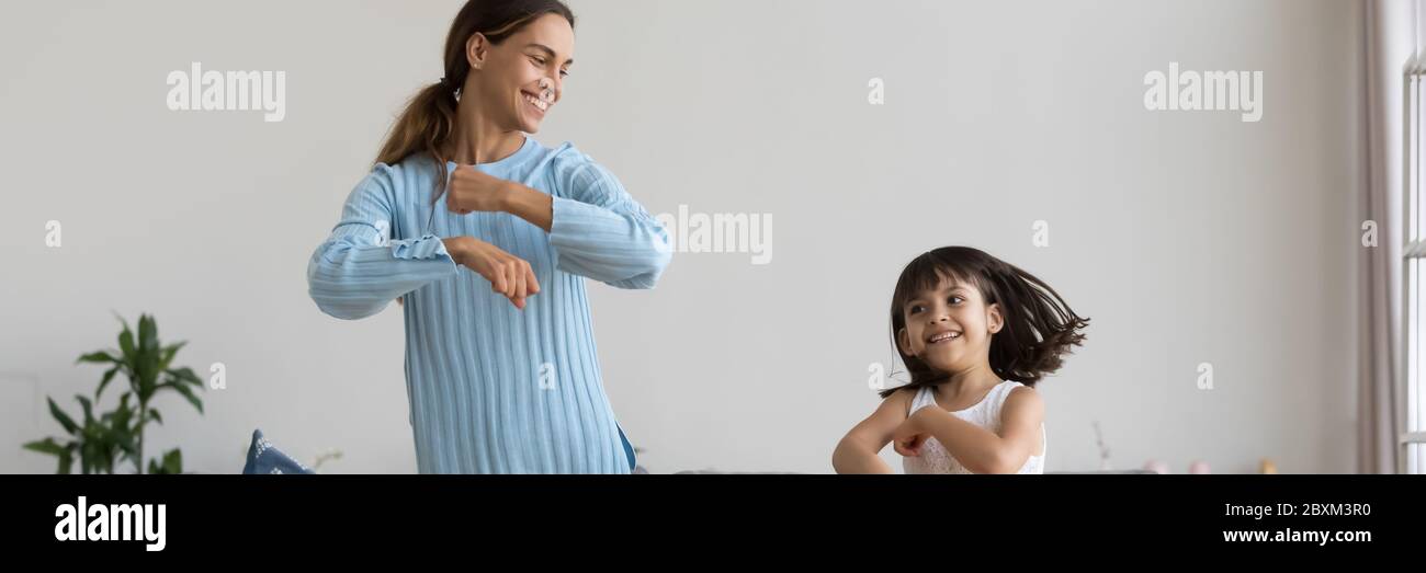 Giovane madre attiva piccola figlia che balla ascoltando musica divertendosi Foto Stock