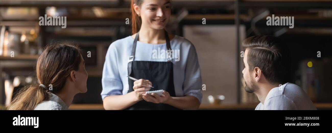 Cameriera tenendo il blocco note pronto prendere ristorante visitatori coppia ordine Foto Stock