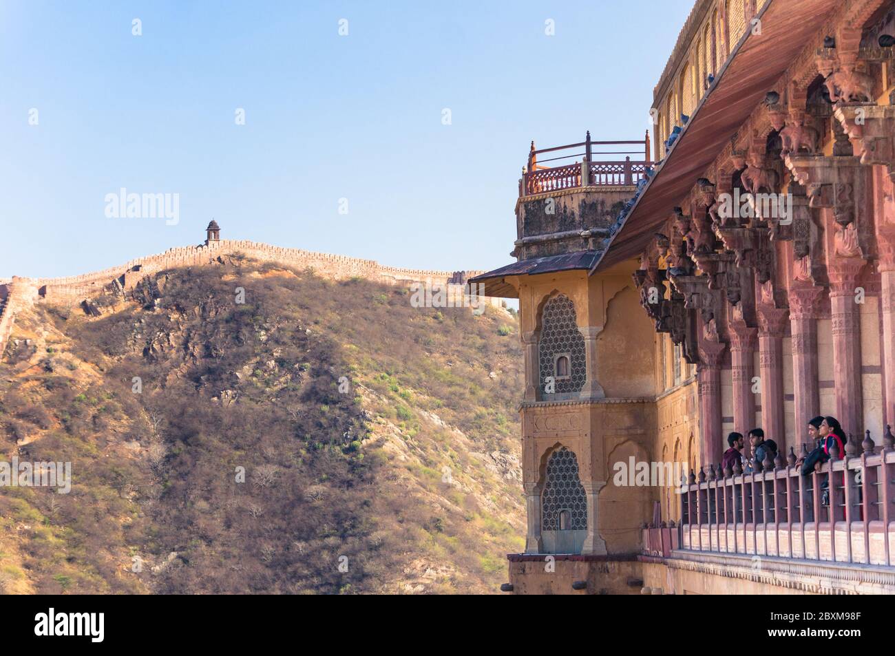 Visitatori a Amer Fort vicino Jaipur, Rajasthan, India che guarda splendidi paesaggi di montagne e colline con vecchie mura di fortificazione Foto Stock