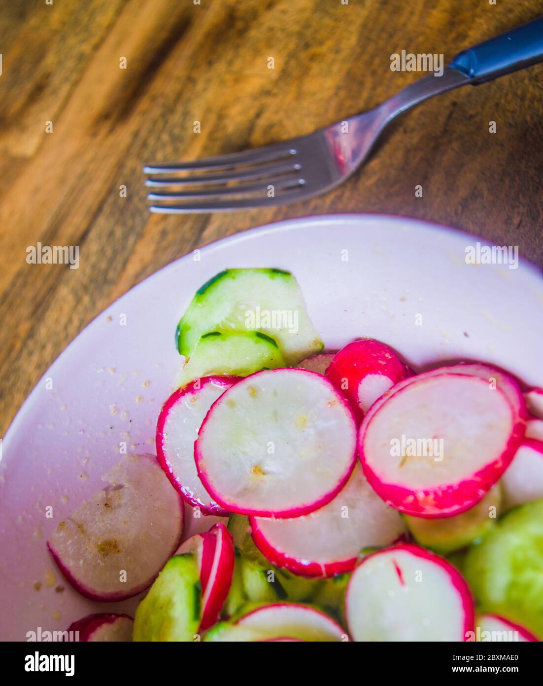 Insalata sana di rafano e zucchine, condita con olio di vinagraitte, sale, pepe, aceto e succo di limone in una ciotola su una tavola di legno indossata dal tempo e dal p. Foto Stock