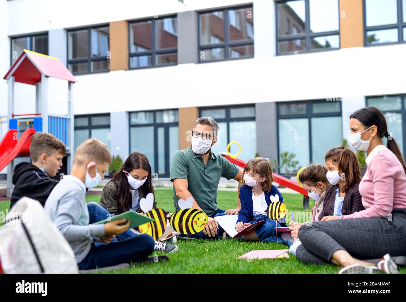 Gruppo di bambini allegri che imparano all'aperto a scuola dopo la quarantena e il blocco del covid-19. Foto Stock