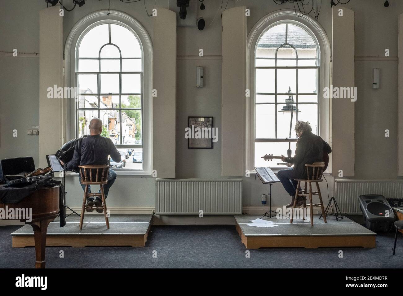 A Presteigne, Galles, Regno Unito, i musicisti John Hymas e Pete Mustil intrattengono i clienti in fila pazientemente fuori dai negozi nella strada alta durante la chiusura Foto Stock