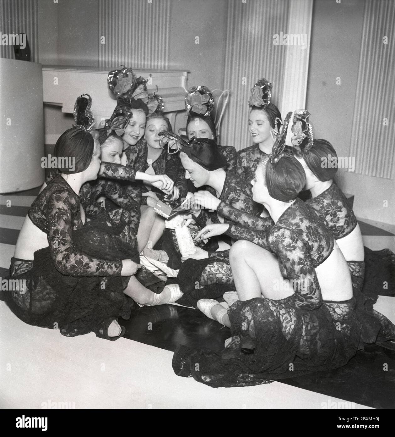Cioccolato negli anni '40. Un gruppo di donne sta mangiando da una scatola di cioccolatini su un set di film. Sembrano tutti interessati ad avere un pezzo di cioccolato. È il marchio Aladdin più venduto della società svedese Marabou che 1939 è stato il primo con l'imballaggio e la vendita di cioccolato. Conteneva 18 dei suoi cioccolatini più venduti. Svezia 1943. Kristoffersson rif D95-3 Foto Stock