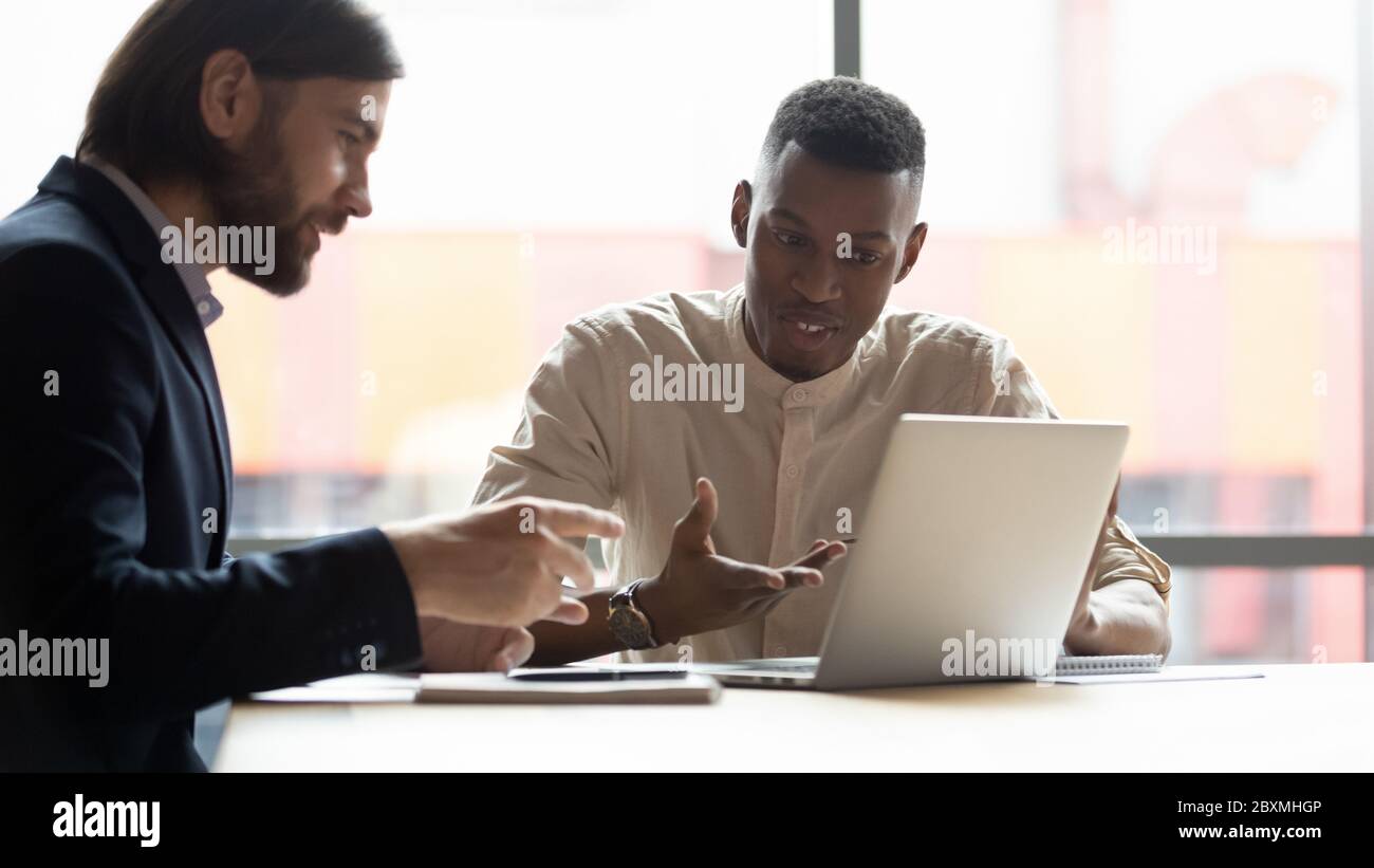 Uomini d'affari multietnici che guardano lo schermo del notebook per discutere di nuove applicazioni Foto Stock