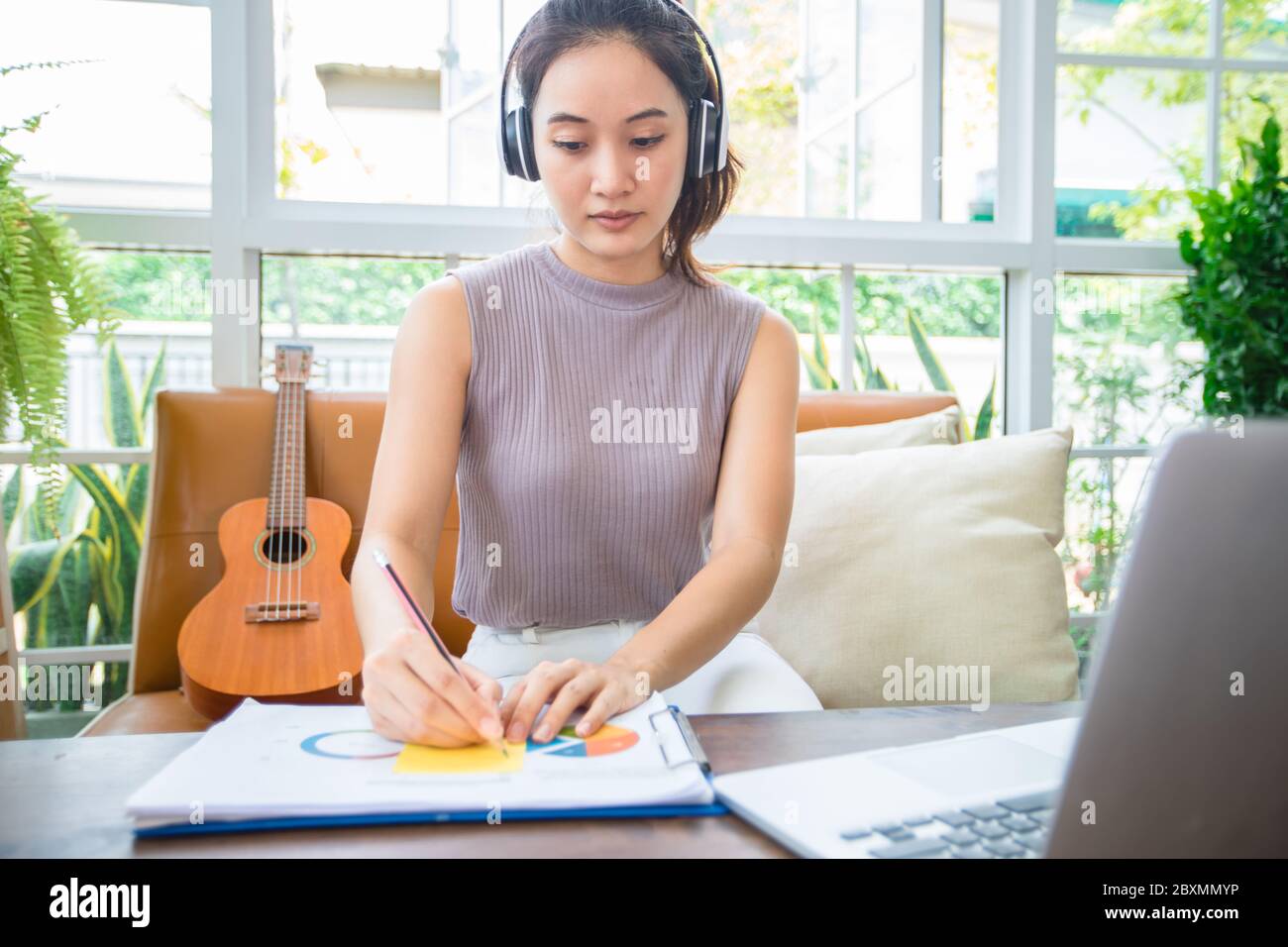 Le donne d'affari asiatiche stanno usando i calcolatori del notebook e indossano le cuffie per le riunioni in linea e lavorare da casa. Foto Stock