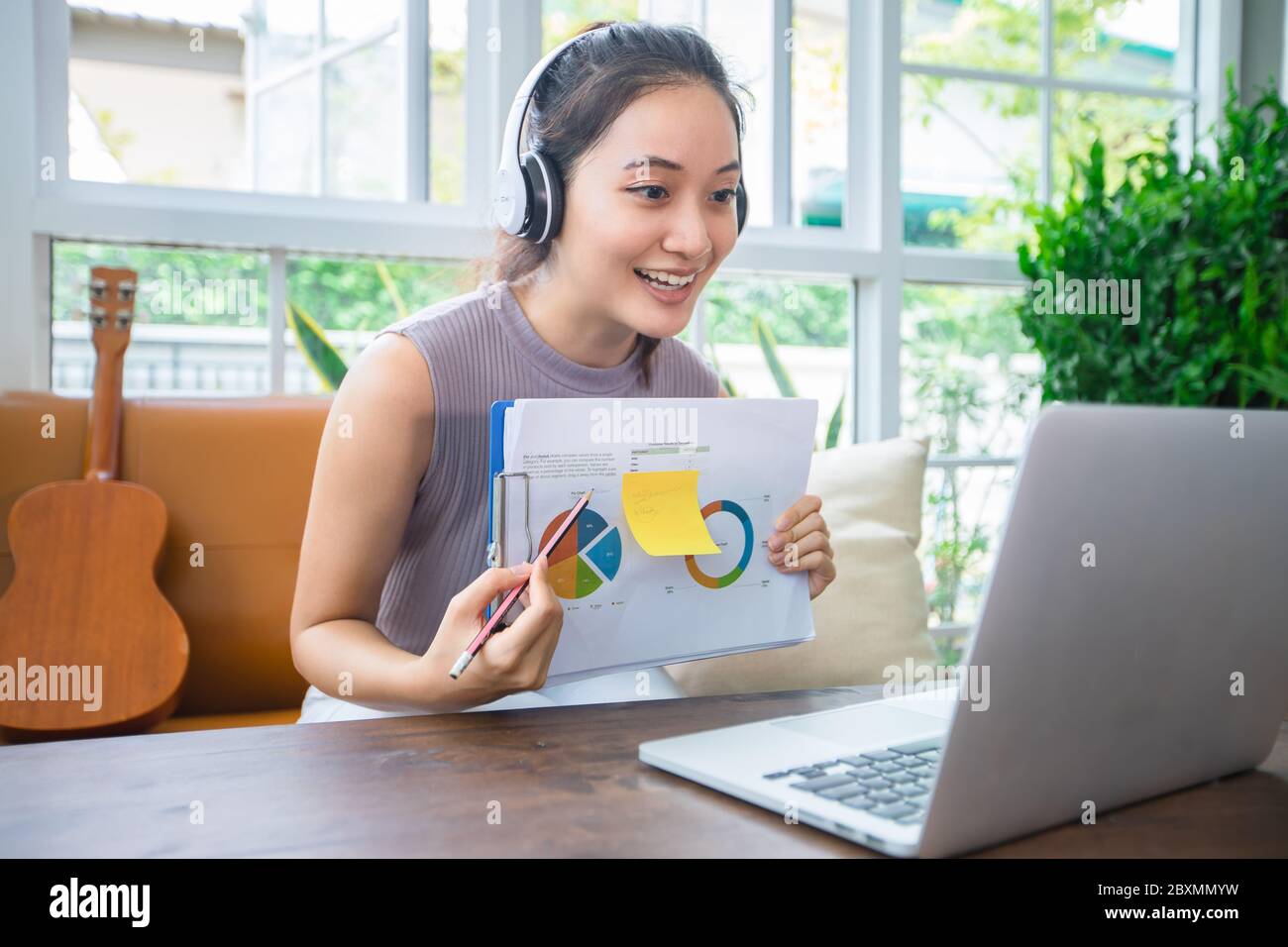Le donne d'affari asiatiche stanno usando i calcolatori del notebook e indossano le cuffie per le riunioni in linea e lavorare da casa. Foto Stock