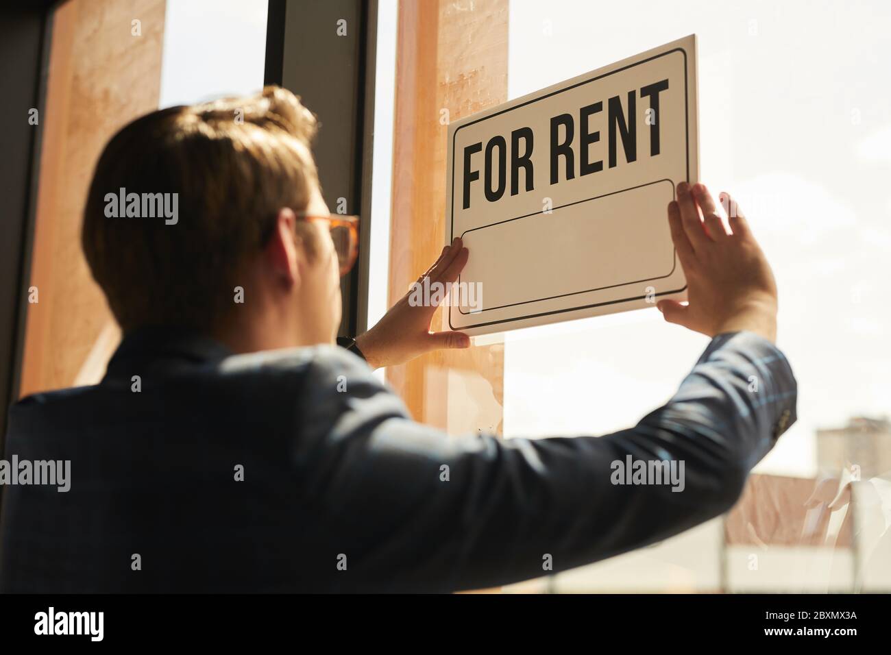 Indietro vista ad agente immobiliare appeso PER L'AFFITTO segno sulla finestra di casa o appartamento, spazio copia Foto Stock
