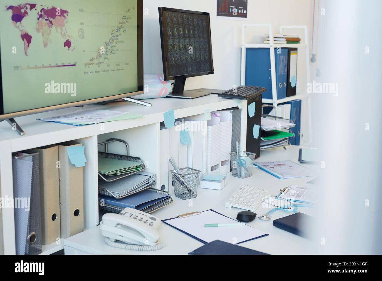 Immagine orizzontale di sfondo di scrivania disordinata in un luogo di lavoro vuoto in una clinica occupata, spazio di copia Foto Stock