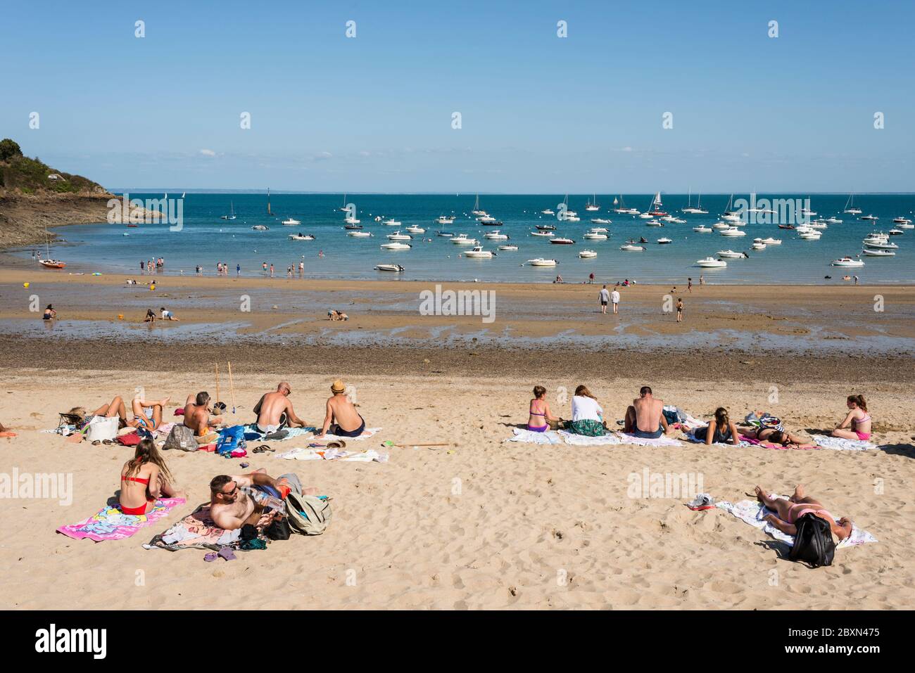 Le persone che godono la giornata estiva sulla spiaggia di sabbia, Port Mer, Cancale, Bretagna, Francia Foto Stock