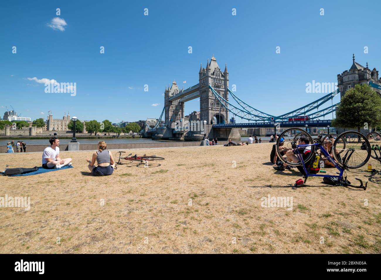 Le persone che si godono la vita all'aperto in una bella giornata di sole sul fiume Tamigi vicino a Tower Bridge, Londra, Regno Unito. Foto Stock