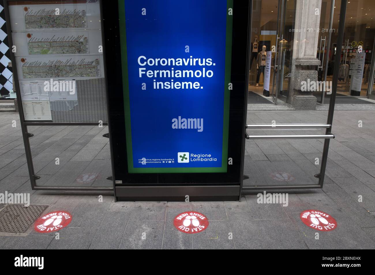 Stazione dei tram con cartelli a distanza sociale sul pavimento per la sicurezza sanitaria durante la crisi del Covid-19, a Milano, Italia. Foto Stock