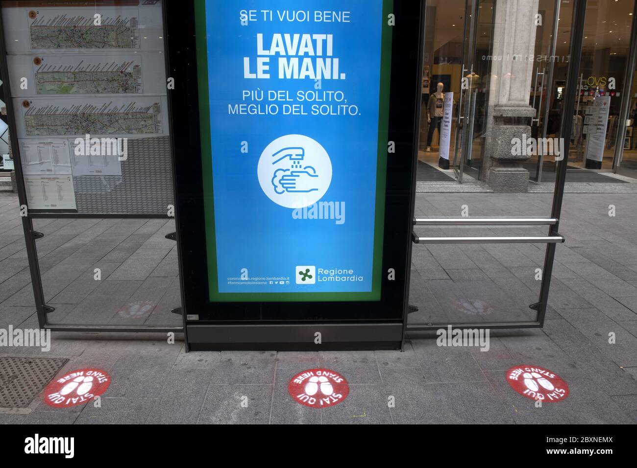 Stazione dei tram con cartelli a distanza sociale sul pavimento per la sicurezza sanitaria durante la crisi del Covid-19, a Milano, Italia. Foto Stock