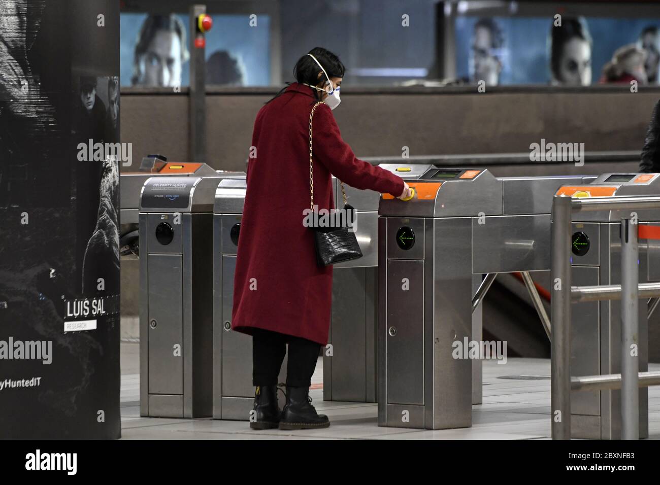 Una donna che indossa una maschera entra nel sottosuolo durante l'emergenza Covid-19, a Milano. Foto Stock