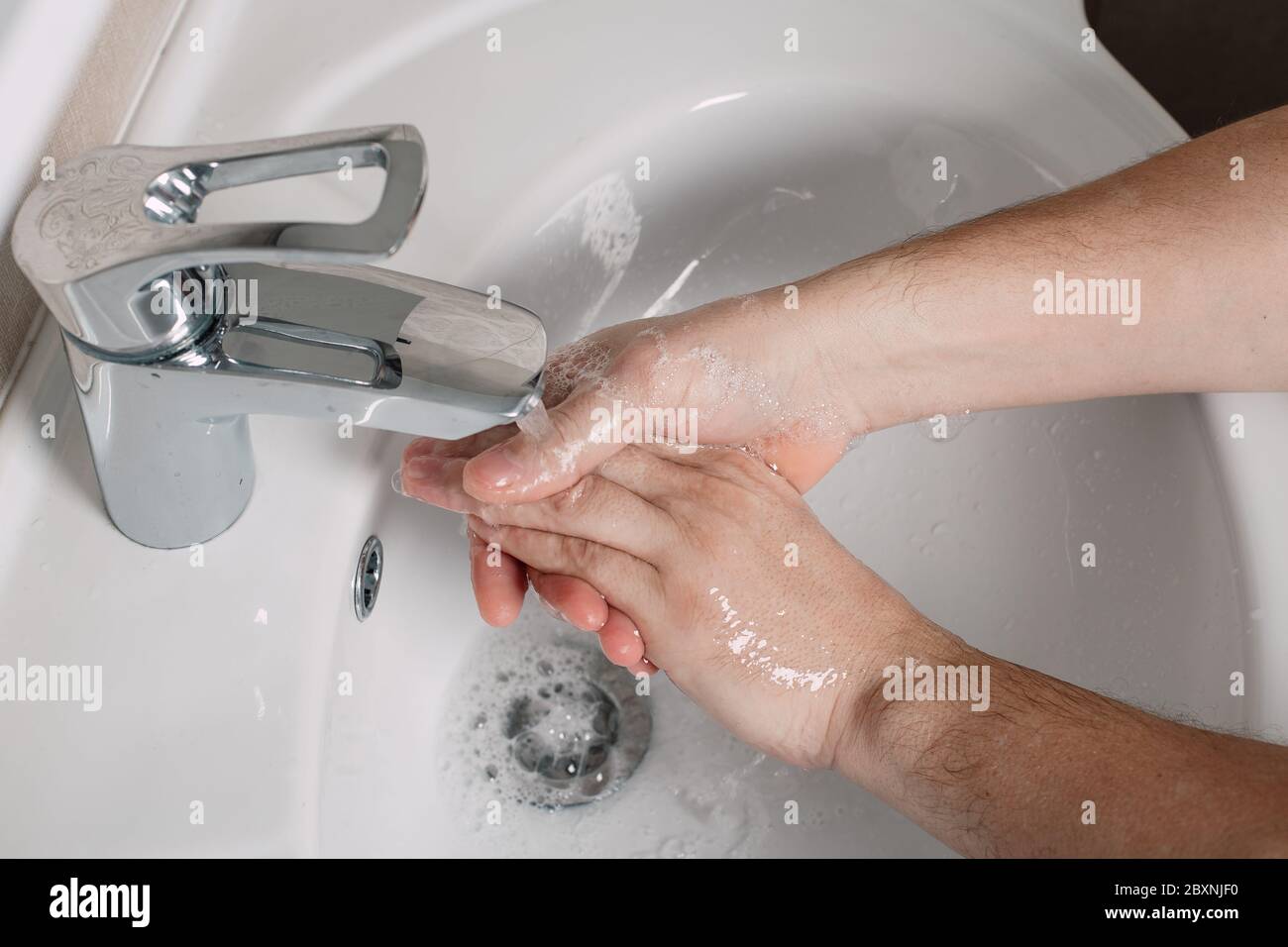 Lavate le mani sotto l'acqua corrente con sapone. Concetto di igiene in dettaglio. Il bagno è dotato di un bellissimo flusso di mani e acqua. Foto Stock