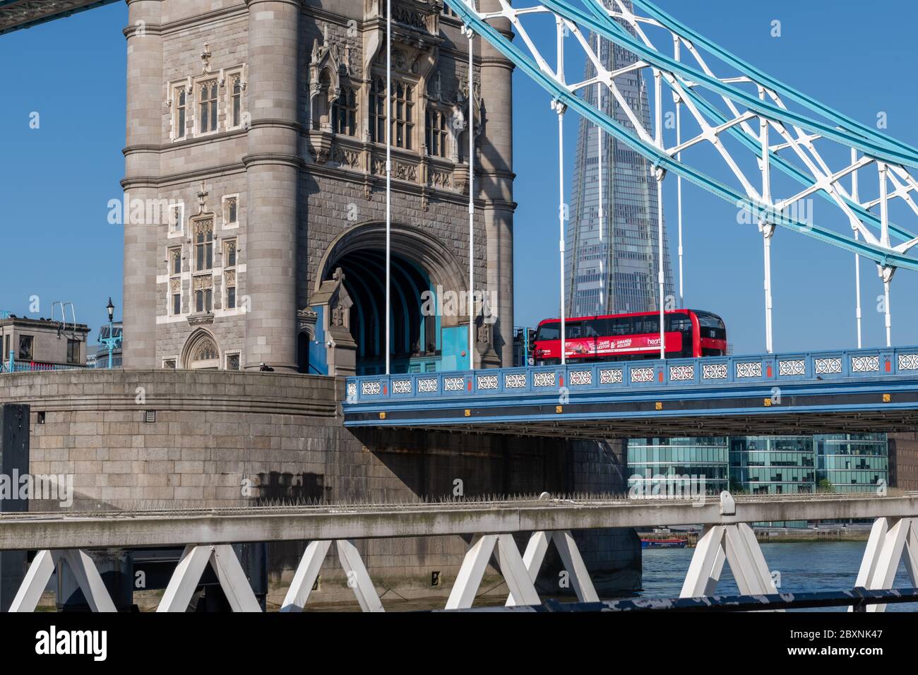Autobus a due piani rosso di Londra che attraversa Tower Bridge in una bella giornata di sole con cielo blu senza nuvole. Foto Stock