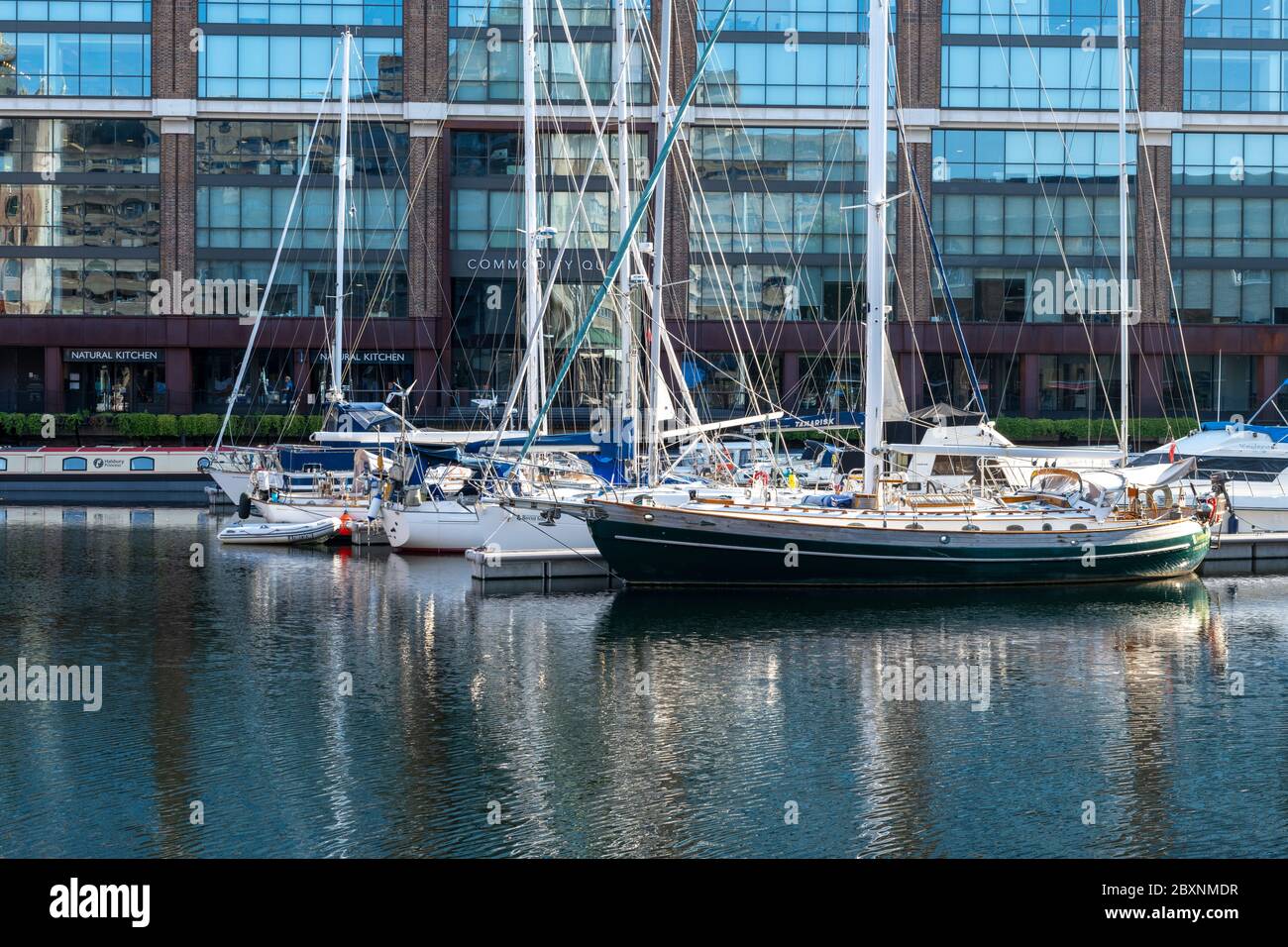 Barche a vela e fusione di costruzione riflessione sulle acque fisse di San Katherine Dock Marina. Foto Stock