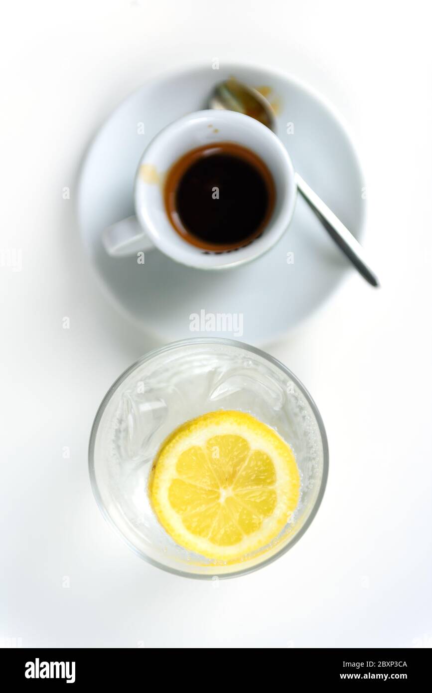 Bicchiere d'acqua frizzante con limone e tazza di caffè. Acqua minerale  ghiacciata con limone e tazza di caffè sul tavolo bianco Foto stock - Alamy