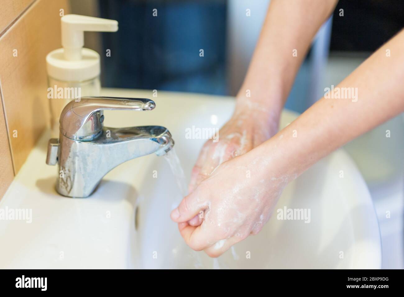 Lavando le mani con sapone sotto il rubinetto con acqua . Concetto di igiene. Foto Stock