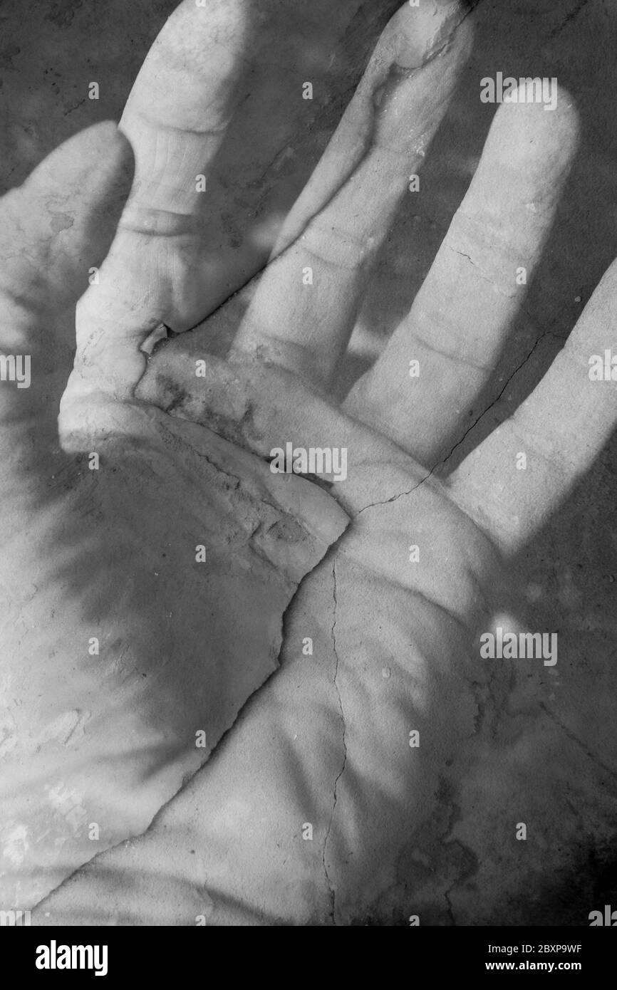 Fotografia in bianco e nero: Doppia esposizione surreale della mano e del calcestruzzo fessurato. Foto Stock