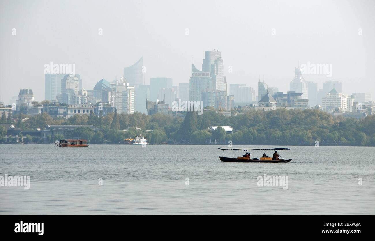 Lago occidentale (Xi Hu) a Hangzhou, provincia di Zhejiang, Cina. Barche sul Lago Ovest con la città di Hangzhou alle spalle. Foto Stock