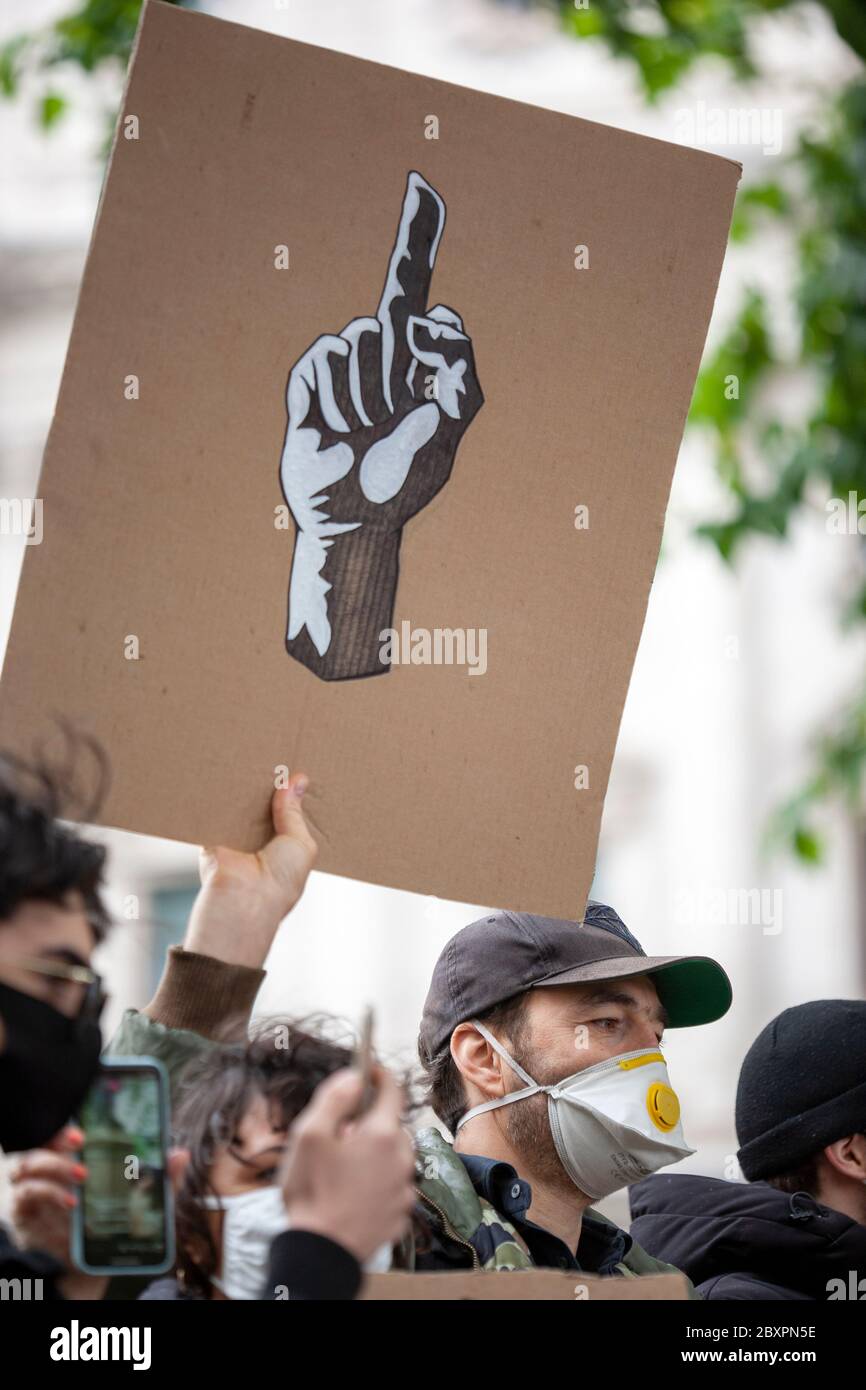 L'uomo, indossando una maschera facciale e un cappello da baseball, tiene  in su un segno che mostra, il simbolo universale per, il gesto del dito  medio, alla protesta BLM UK Foto stock -