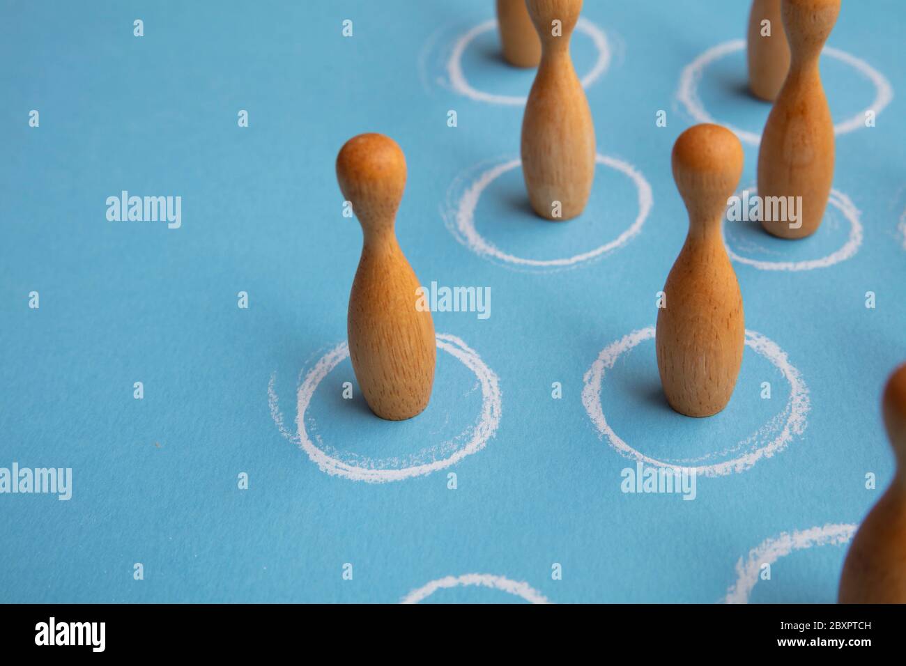 Concetto di allontanamento sociale. Le figure di legno sono in cerchi bianchi Foto Stock