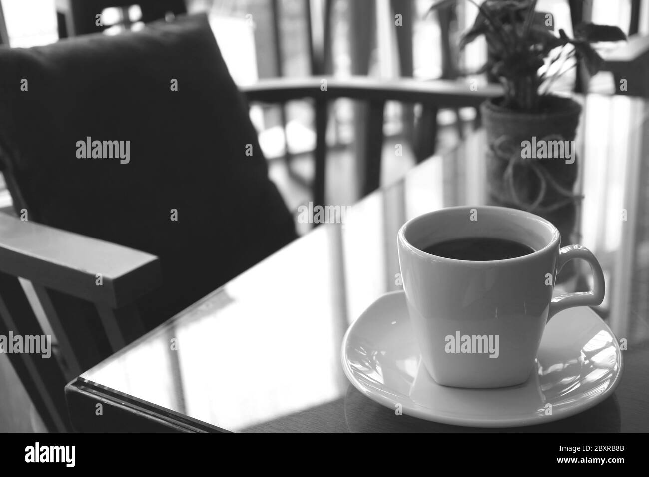 Monotona immagine di una tazza di caffè su un tavolo con sedia vuota Foto Stock