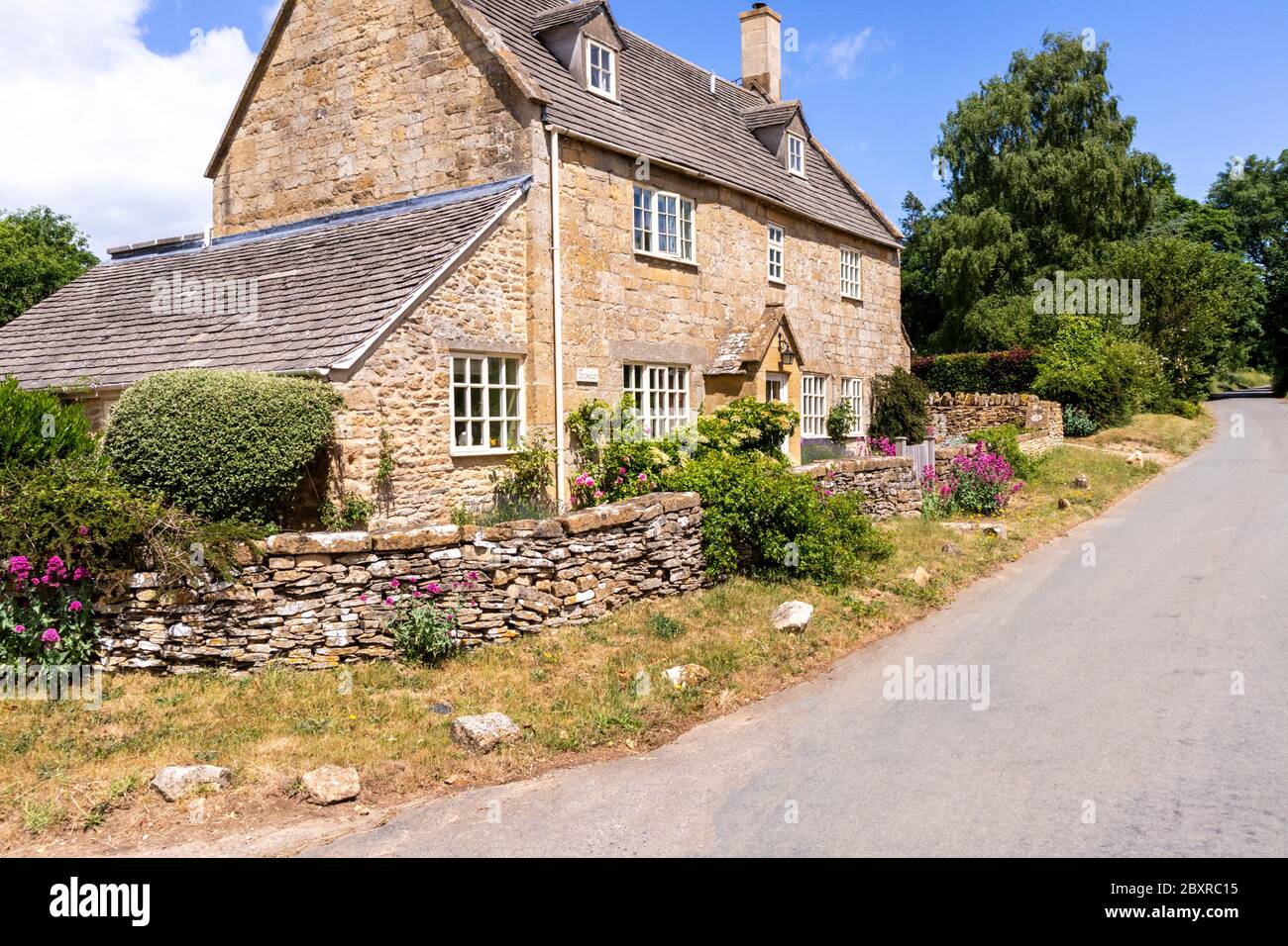 Un cottage di pietra accanto alla corsia nel villaggio di Cutsdean, Gloucestershire UK Foto Stock