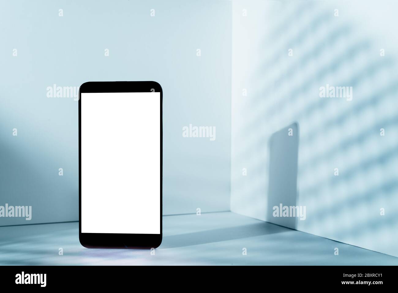 Moderno e minimalista mokup smartphone per la presentazione, in prospettiva davanti all'angolo della parete, con ombre sovrapposte e grigi blu Foto Stock
