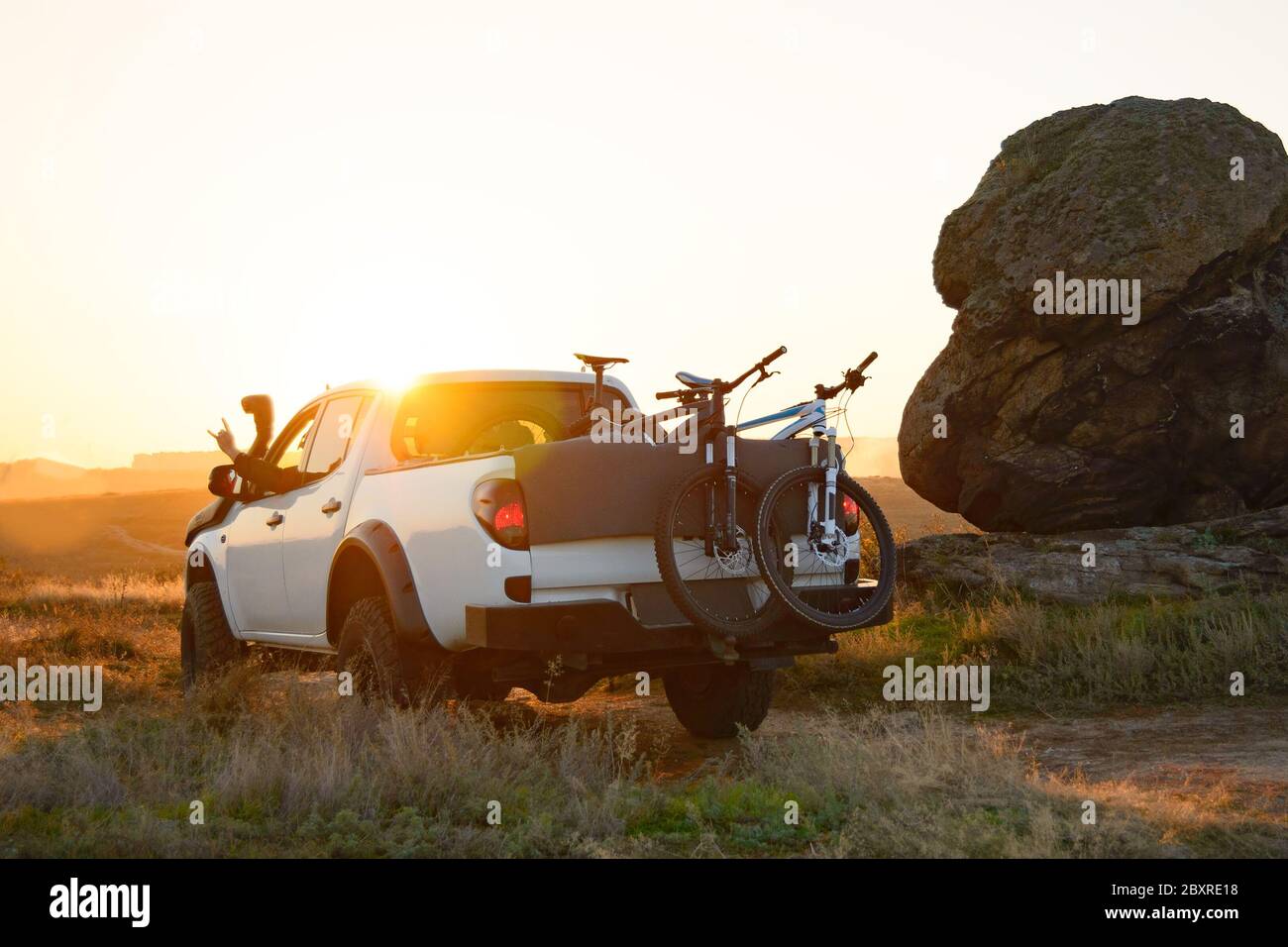 Amici che guidano il pick-up Offroad camion in montagna con biciclette nel corpo al caldo autunno tramonto. MTB Adventure e concetto di viaggio in auto. Foto Stock