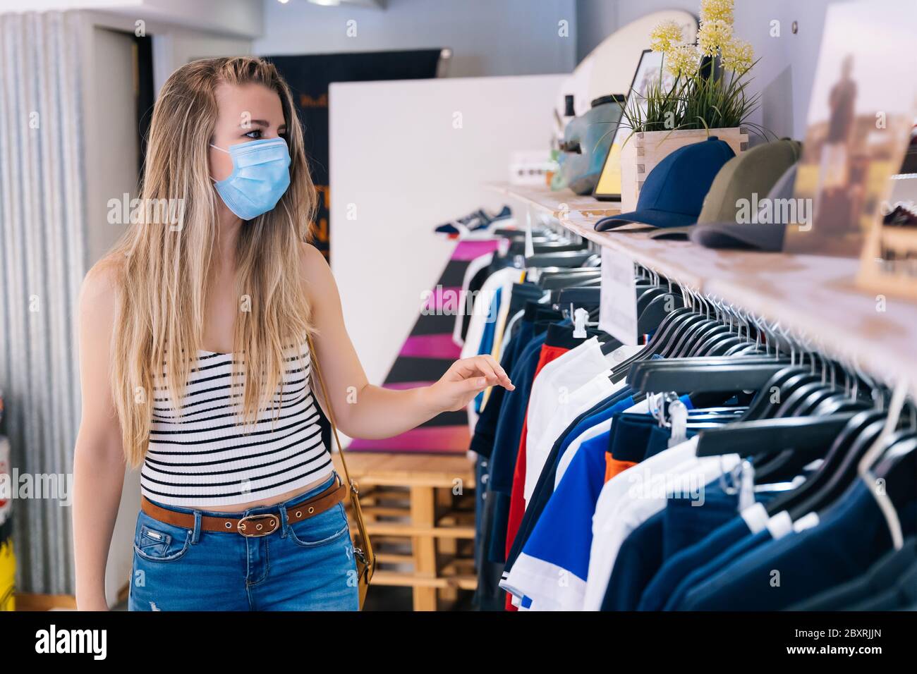 Donna in maschera shopping in un negozio di abbigliamento nella pandemia coronavirus Foto Stock