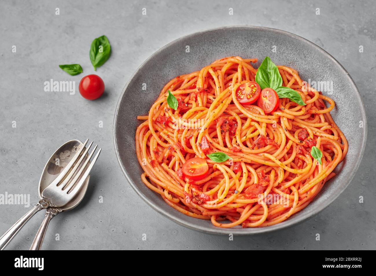 Spaghetti di pomodoro in ciotola grigia su fondo di cemento. La pasta con salsa di pomodoro è un piatto classico della cucina italiana. Popolare cucina italiana Foto Stock