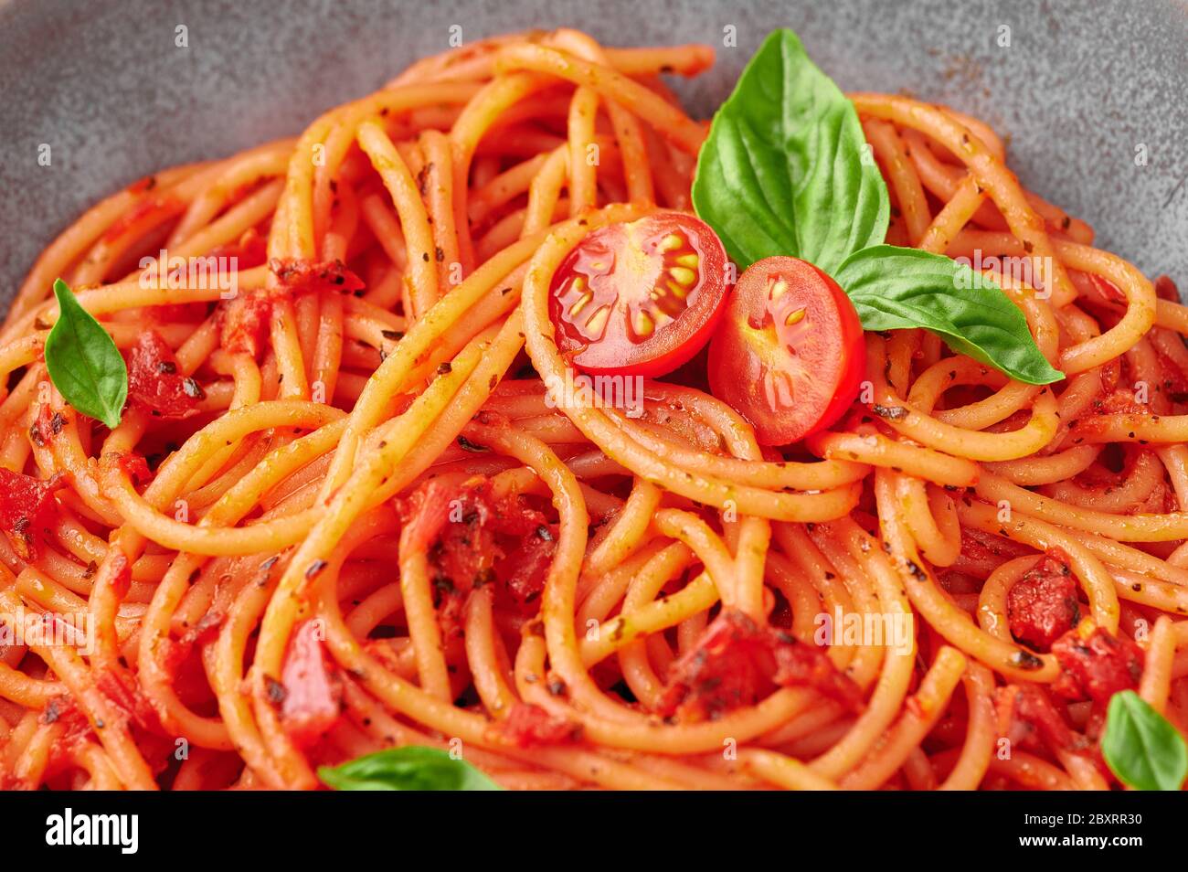 Spaghetti di pomodoro in recipiente grigio. La pasta con salsa di pomodoro è un piatto classico della cucina italiana. Popolare cucina italiana. Primo piano Foto Stock
