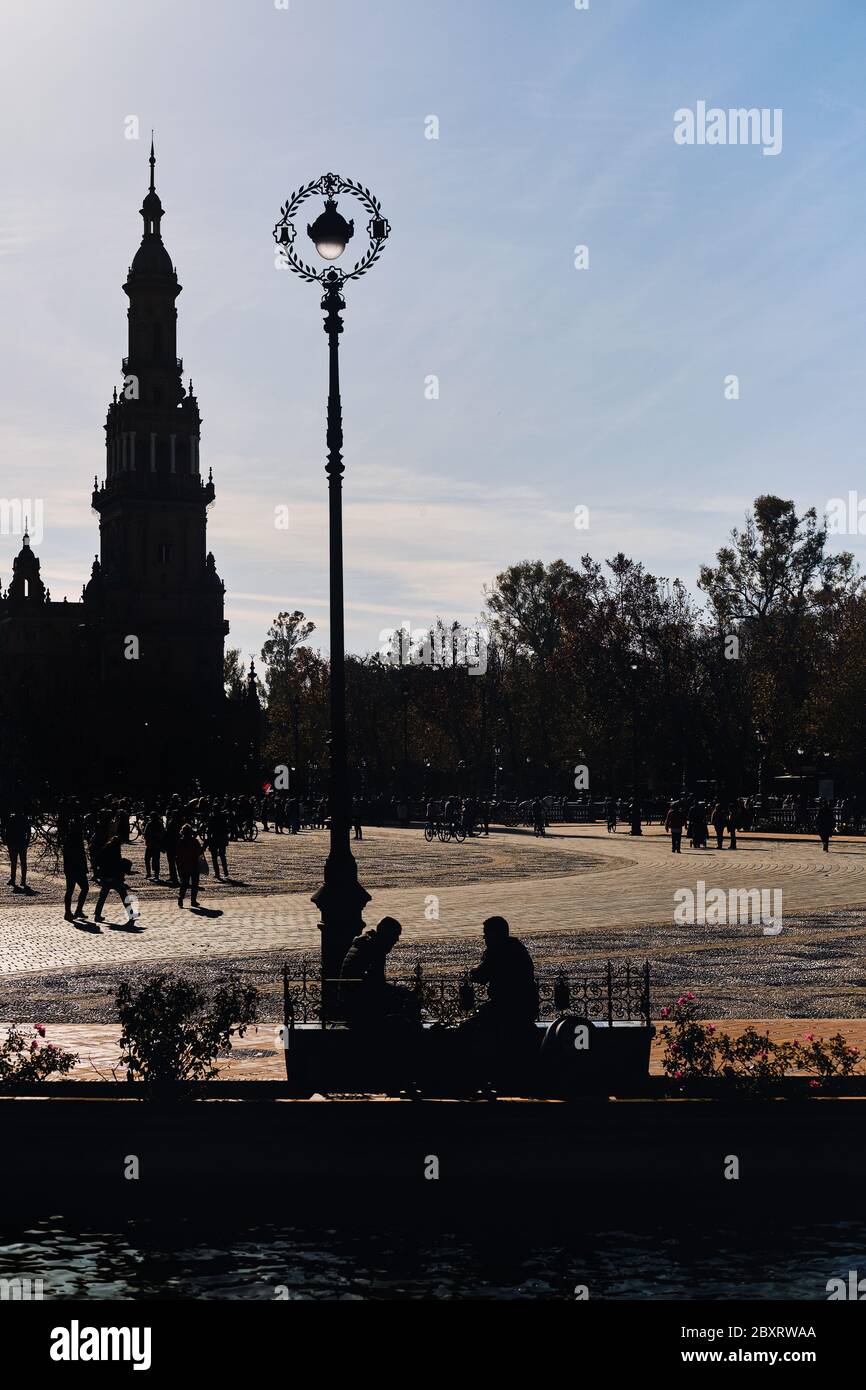 Silhouette architettonica contro il cielo limpido dell'antica torre in Plaza de Espana, molte persone hanno visitato il luogo famoso, principale punto di riferimento della città di Siviglia Foto Stock