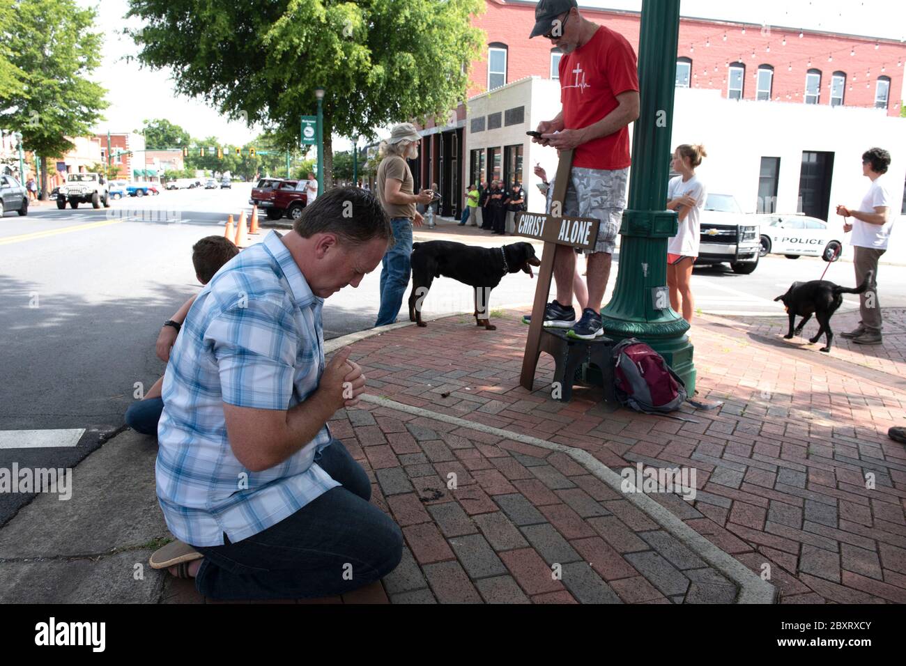 Jasper, Georgia, Stati Uniti. 7 Giugno 2020. I dimostranti Black Lives Matter si riuniscono fuori dal tribunale della contea di Pickens, nella zona rurale della Georgia settentrionale, per protestare contro la brutalità della polizia contro le minoranze. Sono stati accolti da contromanifestanti conservatori e sostenitori del presidente Trump che hanno guardato la manifestazione dall’altra parte della via principale di townÃs. Nella foto: Un uomo locale si inginocchia per pregare attraverso il rally BLM Credit: Robin Rayne/ZUMA Wire/Alamy Live News Foto Stock