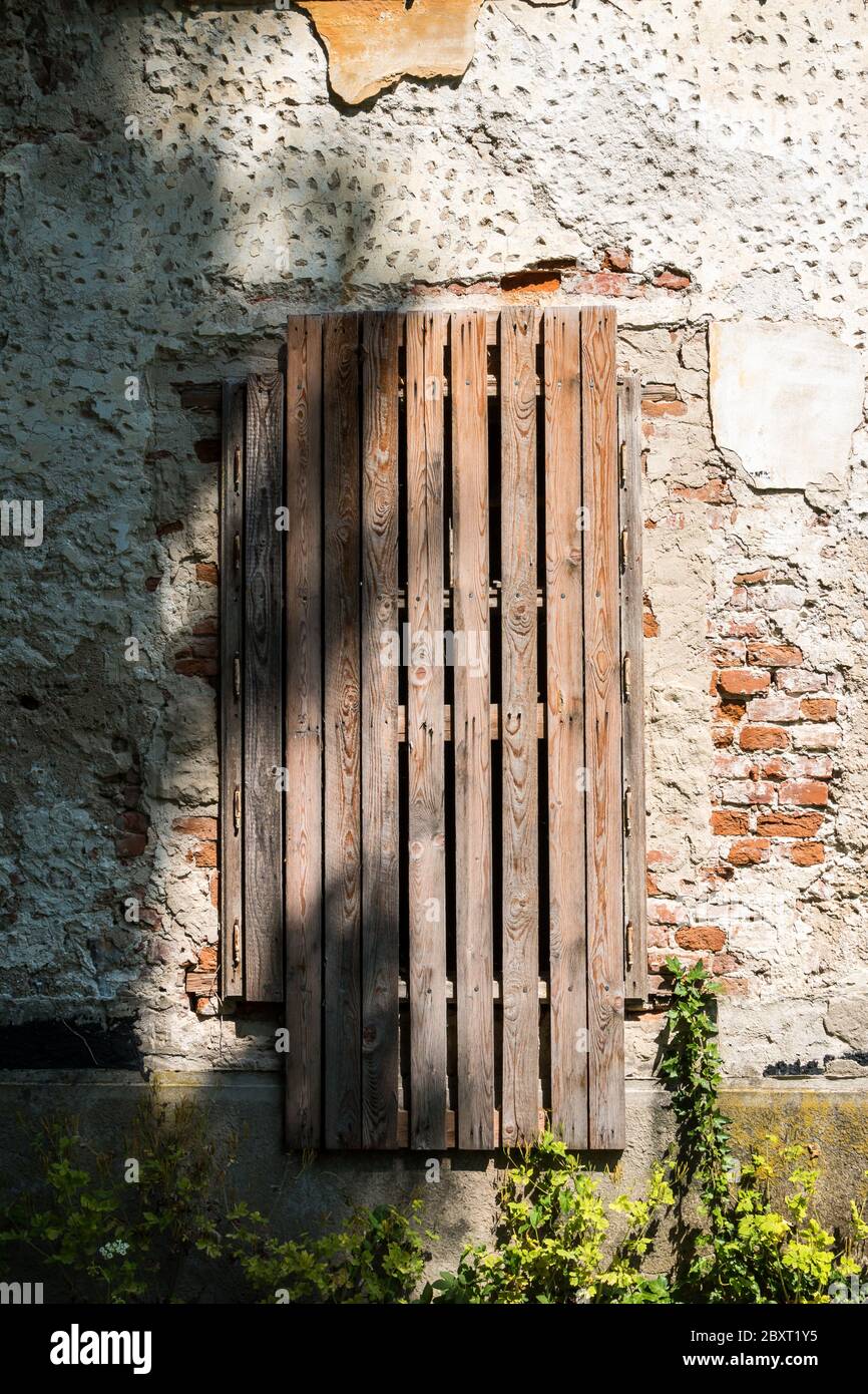 Stagionato e sbucciato dalla facciata di una casa padronale abbandonata. Cancello coperto da listelli di legno. Jablonica, Slovacchia. Foto Stock