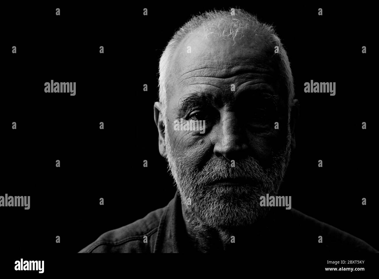 Ritratto in bianco e nero di un vecchio, segnato dalla vita, guardando attentamente nella fotocamera. Foto Stock