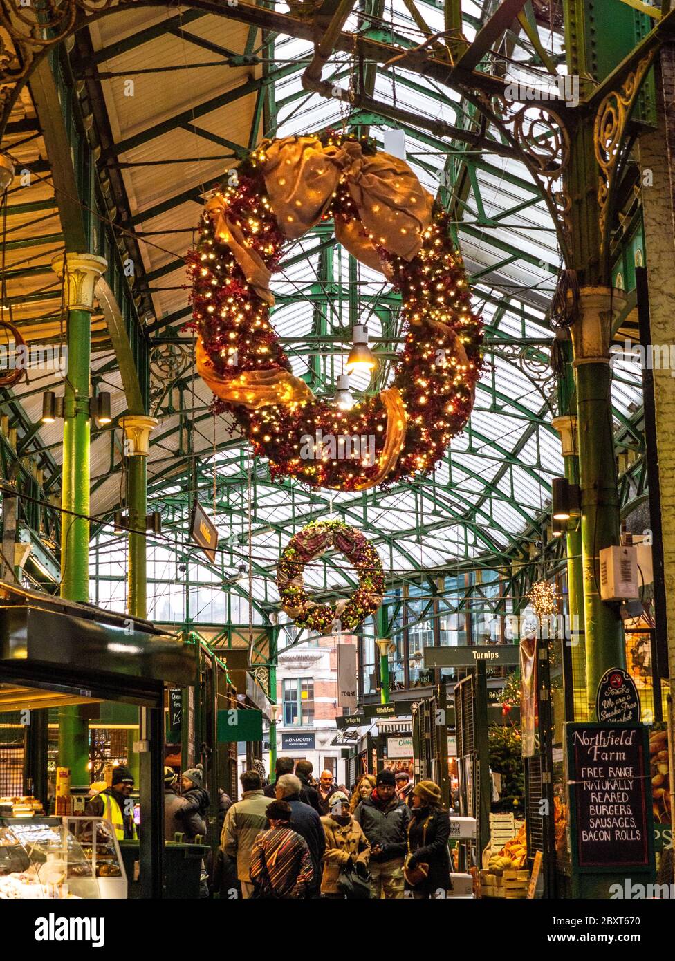 Borough Market luci di Natale e corone all'affollato mercato Borough con varie bancarelle di prodotti illuminate su Southwark London Foto Stock